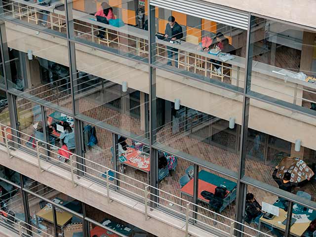 Vista al Edificio C de la Universidad de los Andes con estudiantes en mesas de trabajo